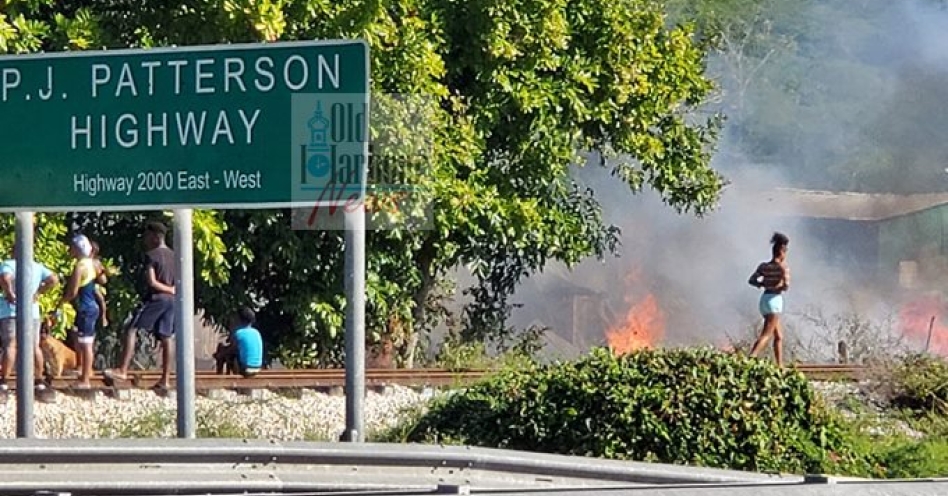 Residents look on after a three-bedroom board house was destroyed by fire in Sharper Lane this morning. (OH News Photo)