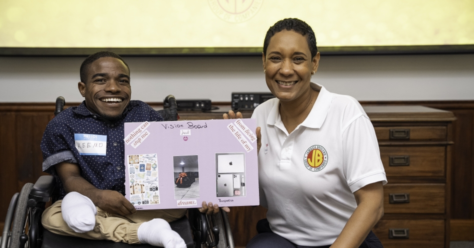 Keemo (left), resident of the Dare to Care Programme is all smiles as he shows off his vision board with Danah Cameron (right), group public relations manager, Jamaica Broilers Group.